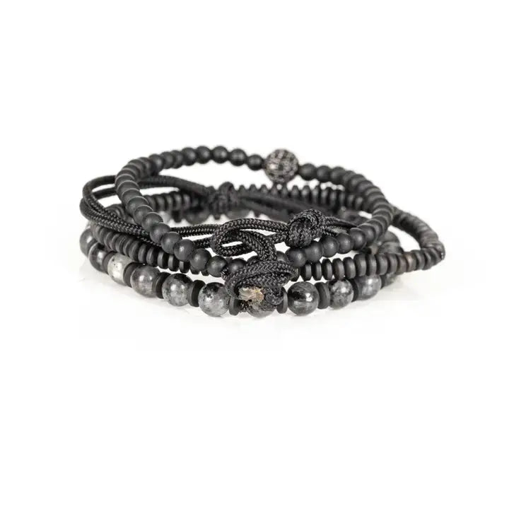 Black and gray layered men’s bracelet set with matte black beads, gray marbled stone accents, braided rope wraps, and pavé centerpiece on white background.