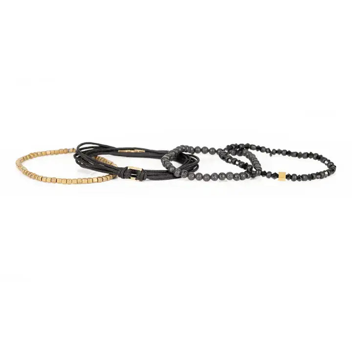 Black and gold layered men’s bracelet set with lava stone beads, gold cube accents, faceted black beads, braided rope wraps, and metallic centerpiece on white background.