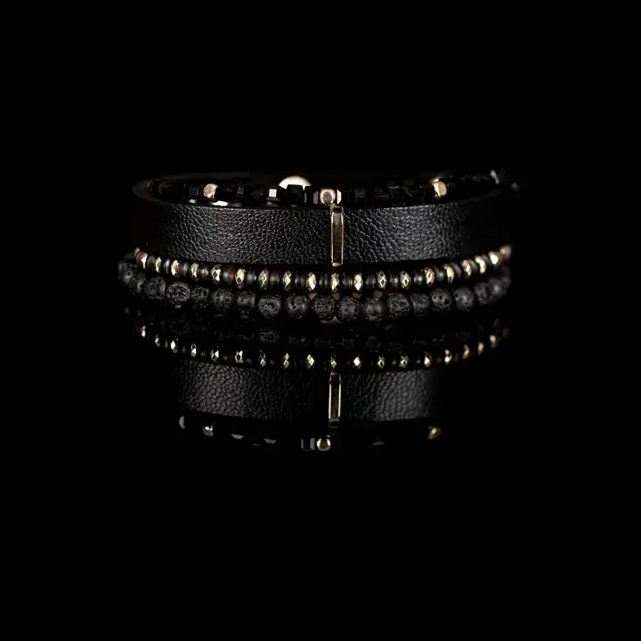 Men’s layered bracelet set featuring a black textured leather cuff, faceted black crystal beads, matte black lava stone beads, metallic hematite accents, and gold-tone spacer details, stacked in a refined black and gold luxury design on a white background.