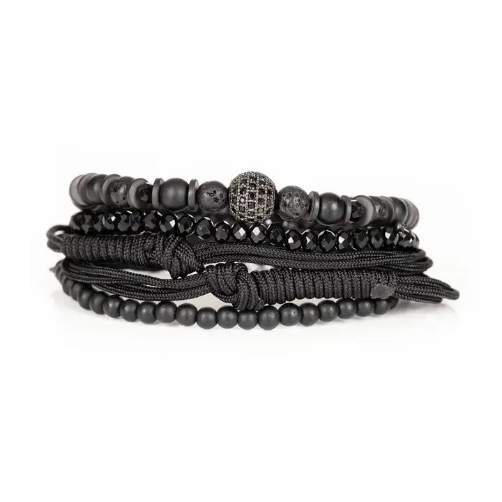 Black layered men’s bracelet set with matte black beads, faceted crystal accents, braided rope wraps, and pavé centerpiece bead on white background.