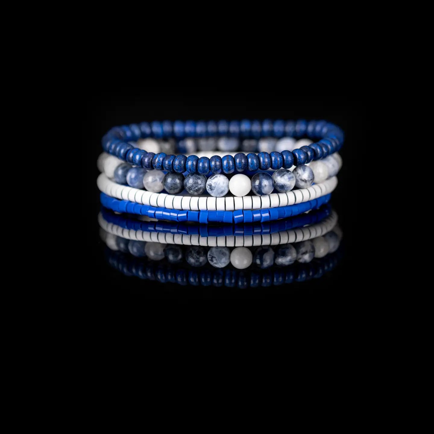 Men’s layered bracelet set featuring deep blue lapis-style heishi beads, blue and white marbled natural stone beads, white howlite heishi beads, and bright blue accent beads, stacked in a sophisticated nautical-inspired luxury design on a white background.