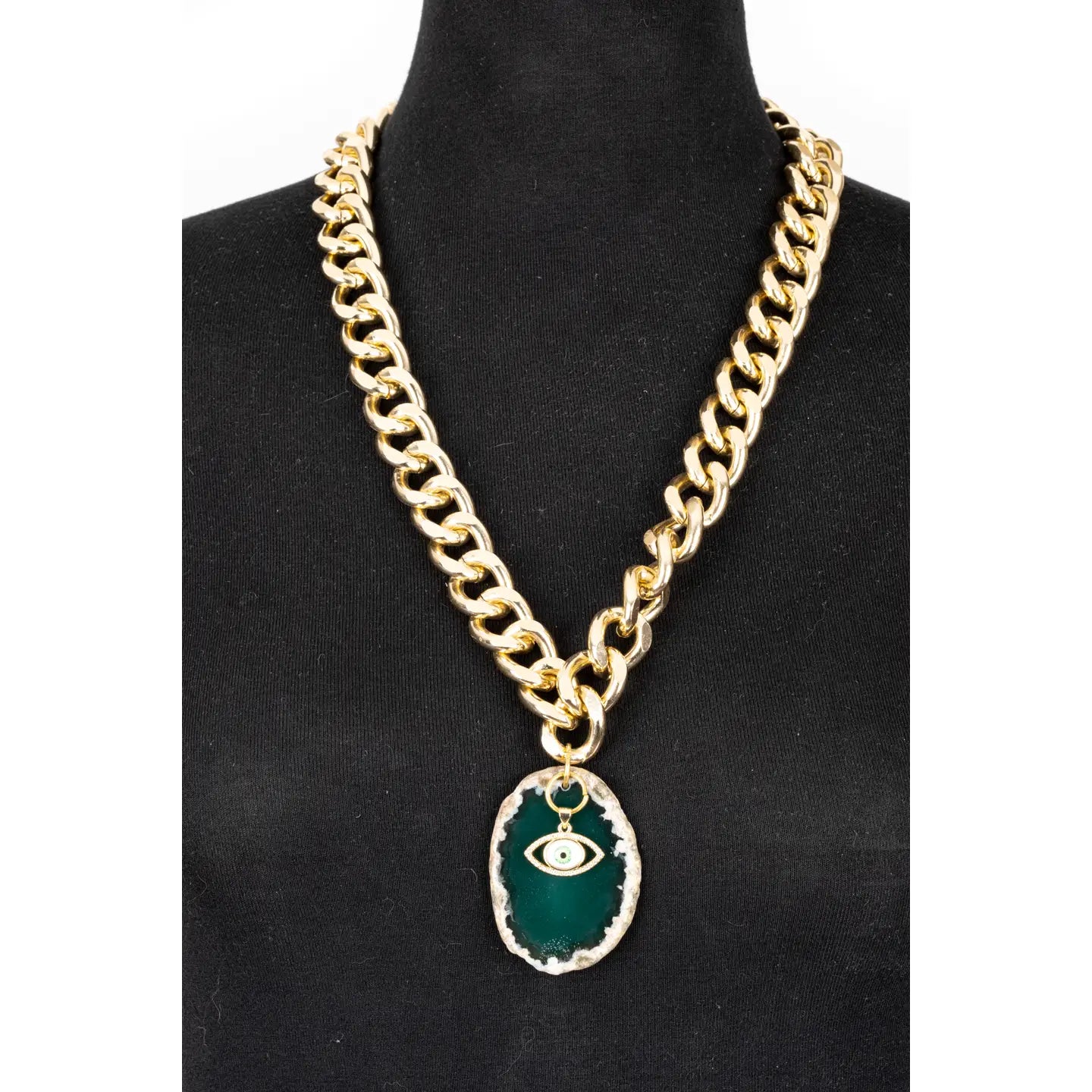 Gold chunky chain necklace with green stone pendant and evil eye charm on white background.