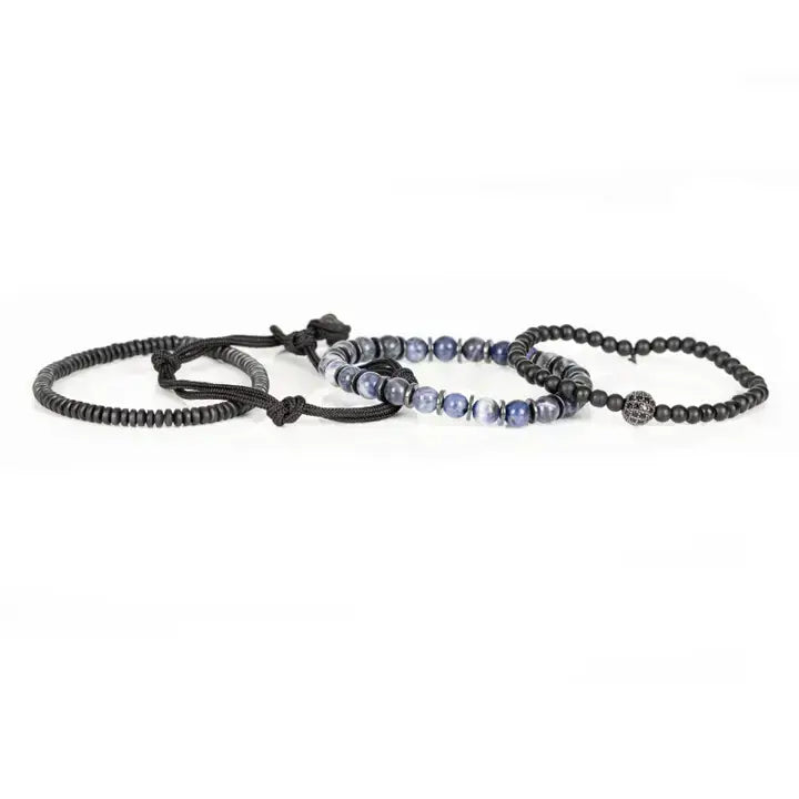 Black and blue layered men’s bracelet set with matte black beads, blue marbled stone accents, braided rope wraps, and pavé centerpiece on white background.