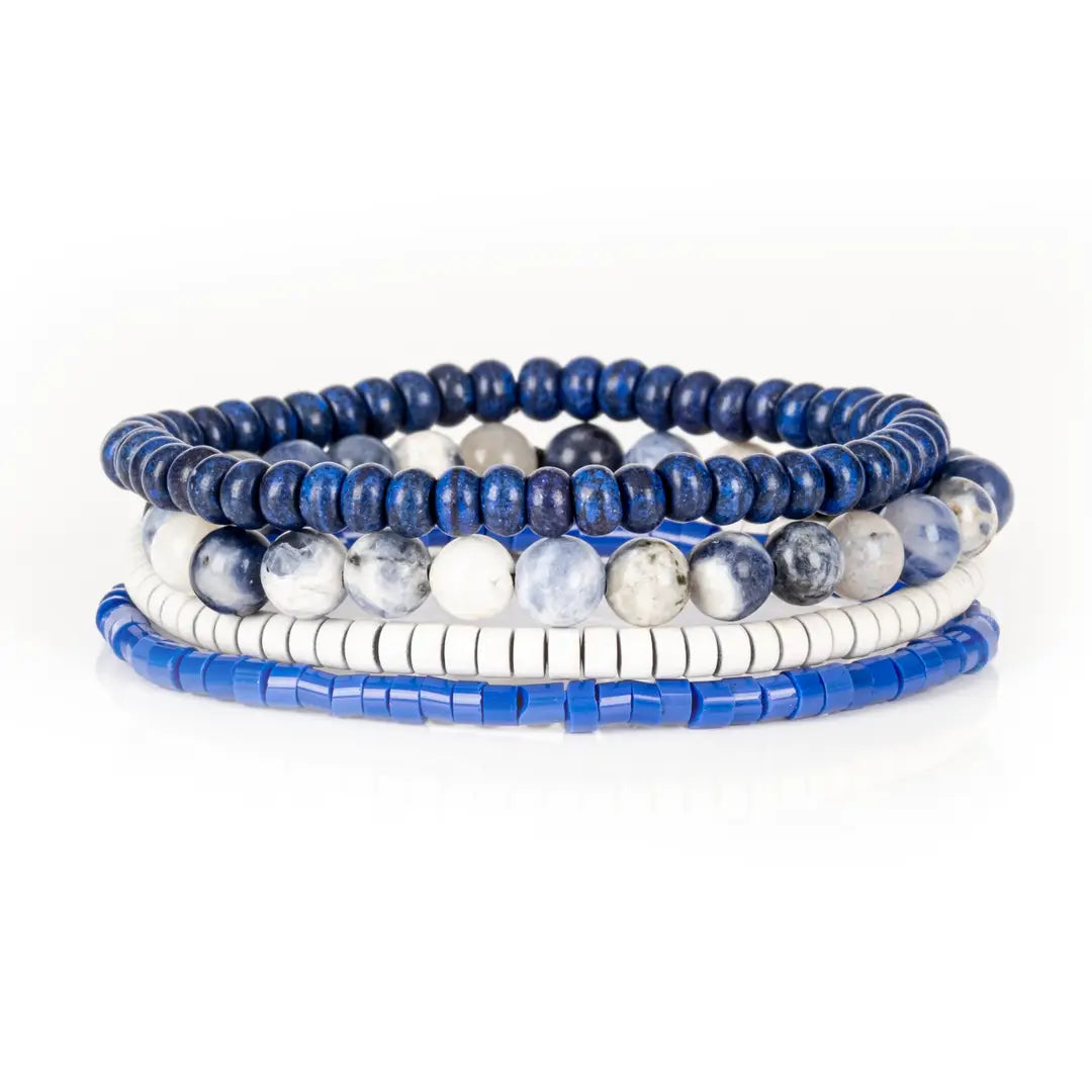 Men’s layered bracelet set featuring deep blue lapis-style heishi beads, blue and white marbled natural stone beads, white howlite heishi beads, and bright blue accent beads, stacked in a sophisticated nautical-inspired luxury design on a white background.