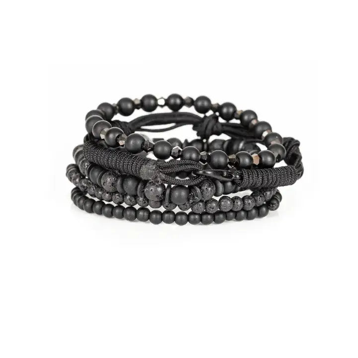 Black layered men’s bracelet set with matte black beads, lava stone accents, marbled centerpiece stone, faceted metallic beads, and braided rope wraps on white background.