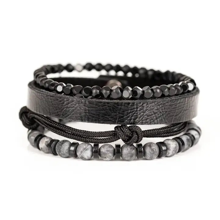 Black multi-layer men’s bracelet featuring faceted black onyx beads, textured black leather band, braided rope layers, marble grey natural stone beads, and metallic spacer accents on a light background.