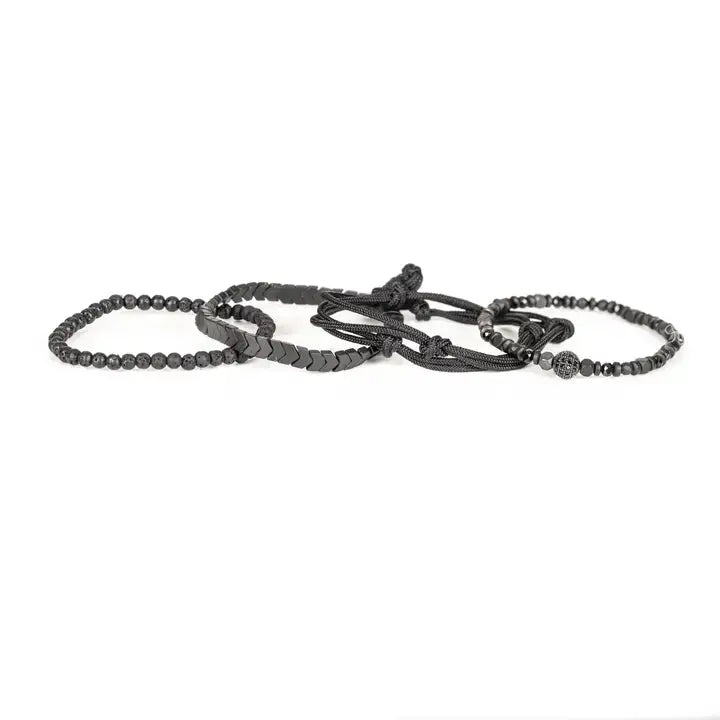 Black layered men’s bracelet set with chevron metal strand, lava stone beads, faceted metallic accents, braided rope wraps, and pavé centerpiece on white background.