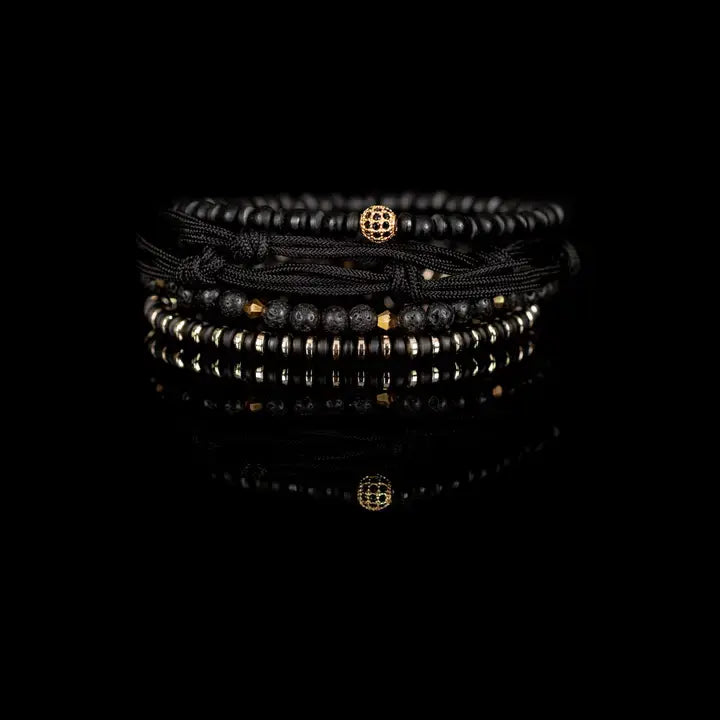 Black and gold layered men’s bracelet set with matte black beads, lava stone accents, gold pavé centerpiece bead, metallic spacers, and braided rope wraps on white background.