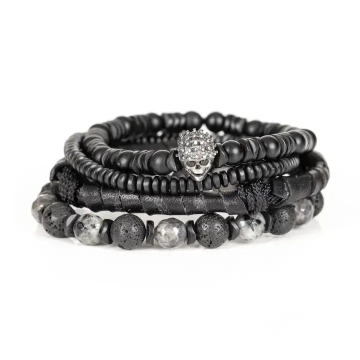Black multi-layer men’s bracelet featuring crystal skull centerpiece, lava stone beads, marble grey natural stones, wrapped leather layer, and matte black bead strands on a light background.