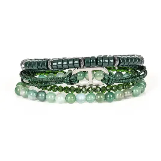 Men’s layered bracelet set featuring dark green heishi beads, green braided cord with a silver-tone centerpiece, faceted green crystal beads, and polished green natural stone beads, stacked in a sophisticated contemporary luxury design on a white background.