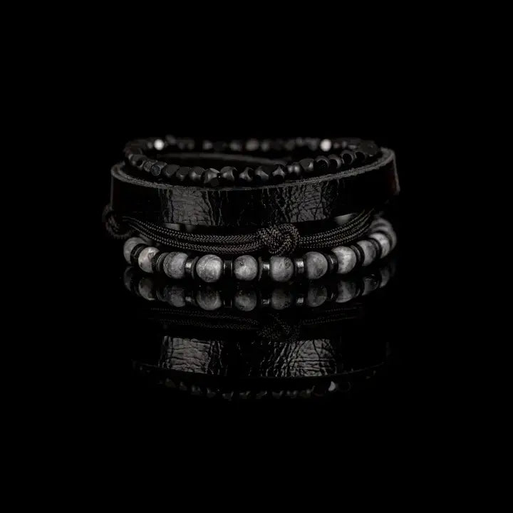 Black multi-layer men’s bracelet featuring faceted black onyx beads, textured black leather band, braided rope layers, marble grey natural stone beads, and metallic spacer accents on a light background.