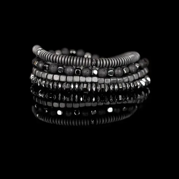 Men’s layered bracelet set featuring silver-tone coil wrap beads, matte black lava stone beads, polished hematite cube beads, faceted hematite crystal beads, and metallic spacer accents, stacked in a sleek industrial luxury design on a white background.
