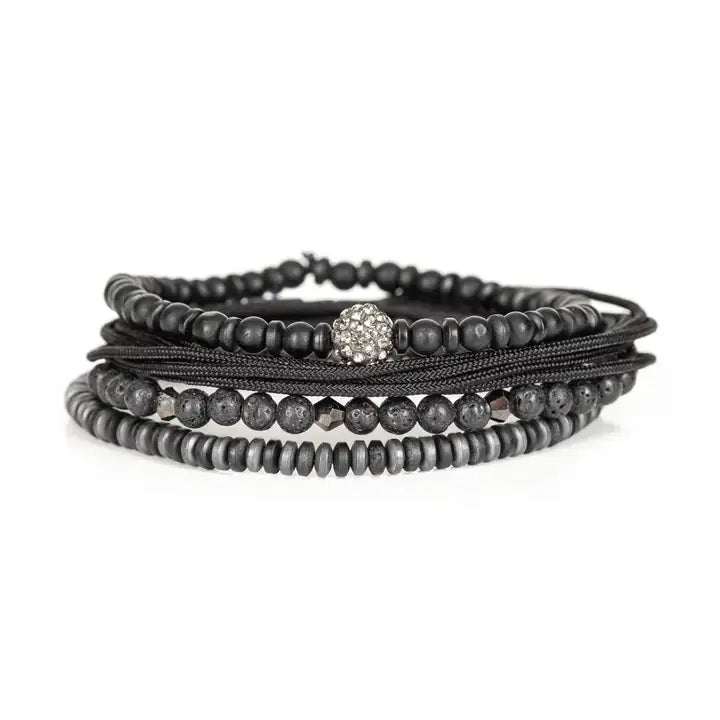 Black multi-layer men’s bracelet featuring matte black beads, lava stone accents, crystal centerpiece bead, braided rope layers, faceted metallic details, and hematite disc strands on a light background.