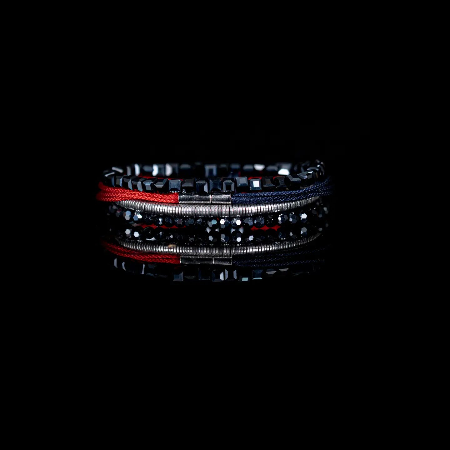 Men's layered bracelet set featuring faceted black crystal beads, polished hematite accents, silver-tone spacer beads, and woven navy and red cord details arranged in a stacked design on a white background.