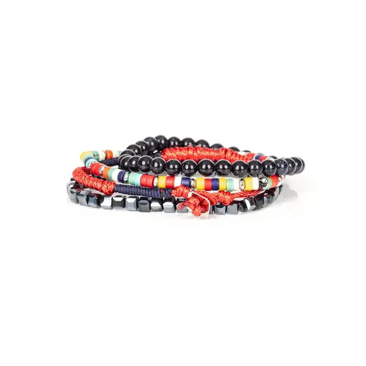 Men’s layered bracelet set featuring glossy black onyx-style beads, multicolor seed beads, red woven cord, navy braided cord, and faceted hematite cube beads, stacked in a bold contemporary luxury design on a white background.