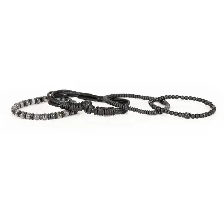 Black layered men’s bracelet set with matte black beads, braided rope wraps, and gray marbled stone accents on white background.