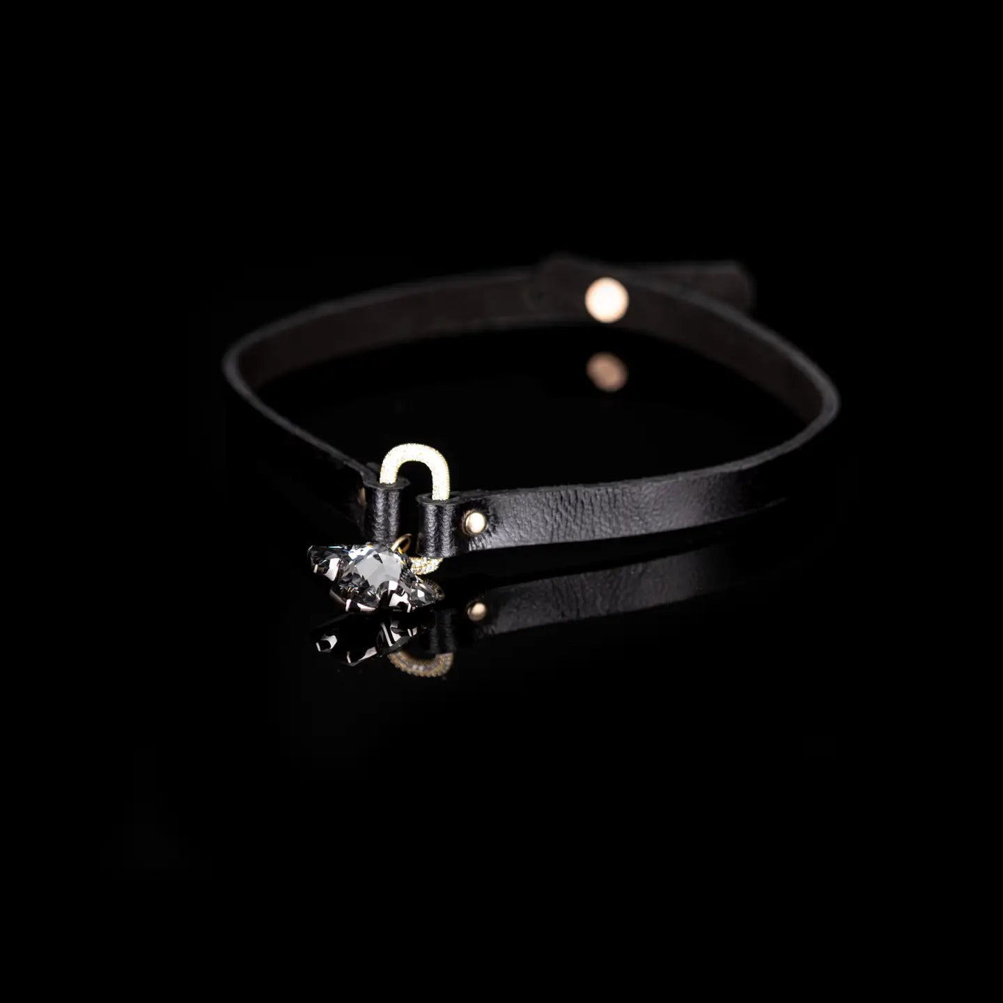 Black leather choker with a crystal oval connector and a faceted crystal cross pendant, displayed on a white background.