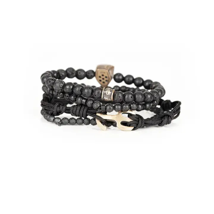 Black layered men’s bracelet set with lava stone beads, matte black beads, metallic mask centerpiece, faceted crystal accents, and braided rope wraps on white background.