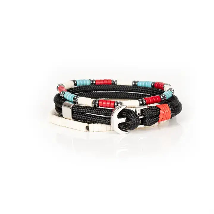 Men’s layered bracelet set featuring black braided cord, white heishi beads, turquoise and red disc beads, silver-tone accents, and hematite spacer beads, stacked in a contemporary bohemian luxury design on a white background.