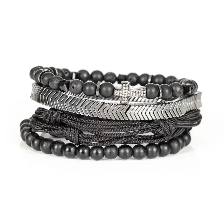 Black and silver layered men’s bracelet set with matte black beads, silver chevron metal bar, pavé cross detail, and braided rope wraps on white background.