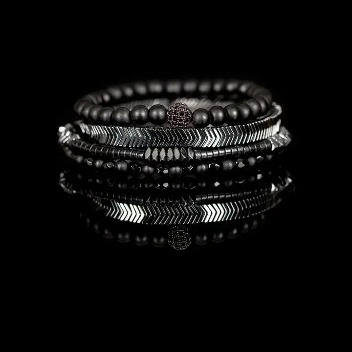 Black multi-layer men’s bracelet featuring matte black onyx beads, silver chevron metal bar, faceted black crystal beads, pyramid-cut hematite accents, and layered metallic details on a light background.