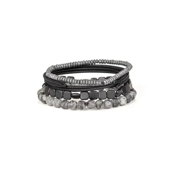 Men’s layered bracelet set featuring gray marbled natural stone beads, polished black hematite cube beads, black braided cord wraps, and silver-gray heishi beads, stacked in a sleek monochromatic luxury design on a white background