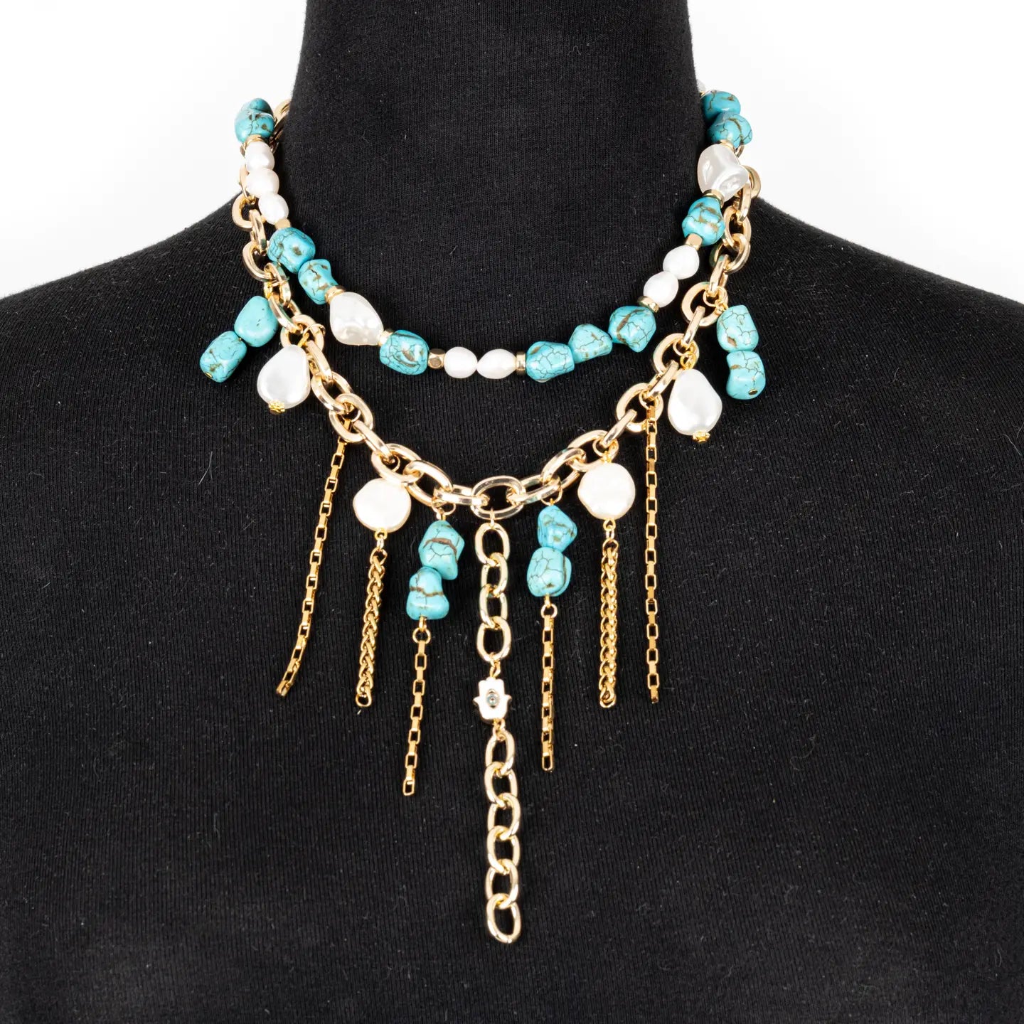 Layered turquoise and white beaded necklace with gold chain details and dangling chain accents on a white background.