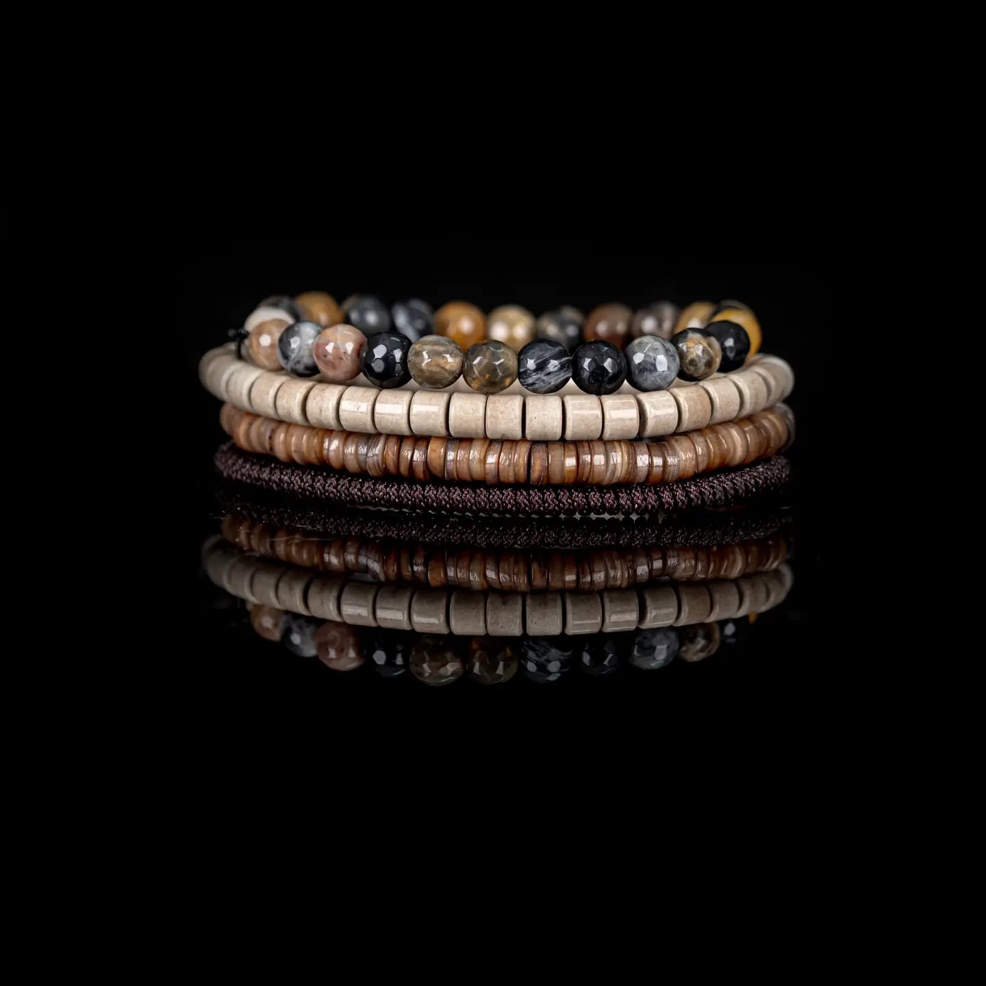 Men's layered bracelet set featuring faceted natural agate stone beads in amber, cream, black, and brown tones with beige heishi beads and brown woven cord accents on a white background.