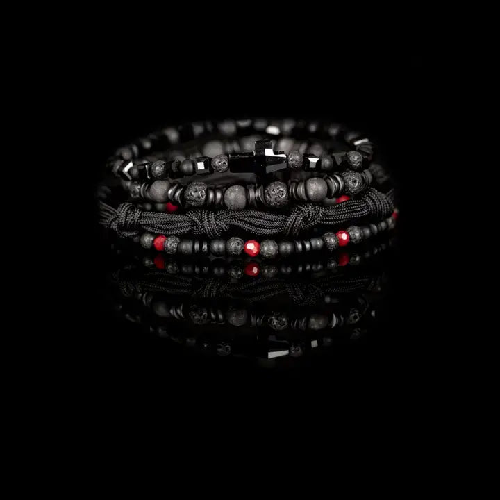 Black multi-layer men’s bracelet set featuring lava stone beads, faceted black onyx, braided rope bands, black cross centerpiece, and subtle red accent beads on a light background.