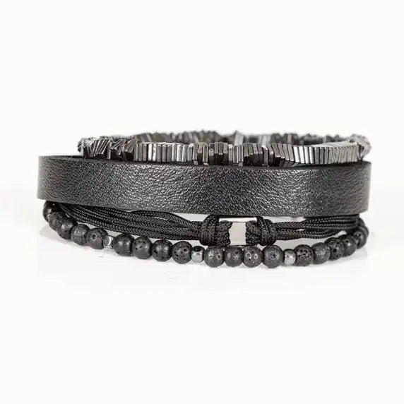 Men’s layered bracelet set featuring a black textured leather cuff, matte black lava stone beads, black braided cord wrap, and gunmetal geometric metal beads with industrial detailing, stacked in a rugged modern luxury design on a white background.