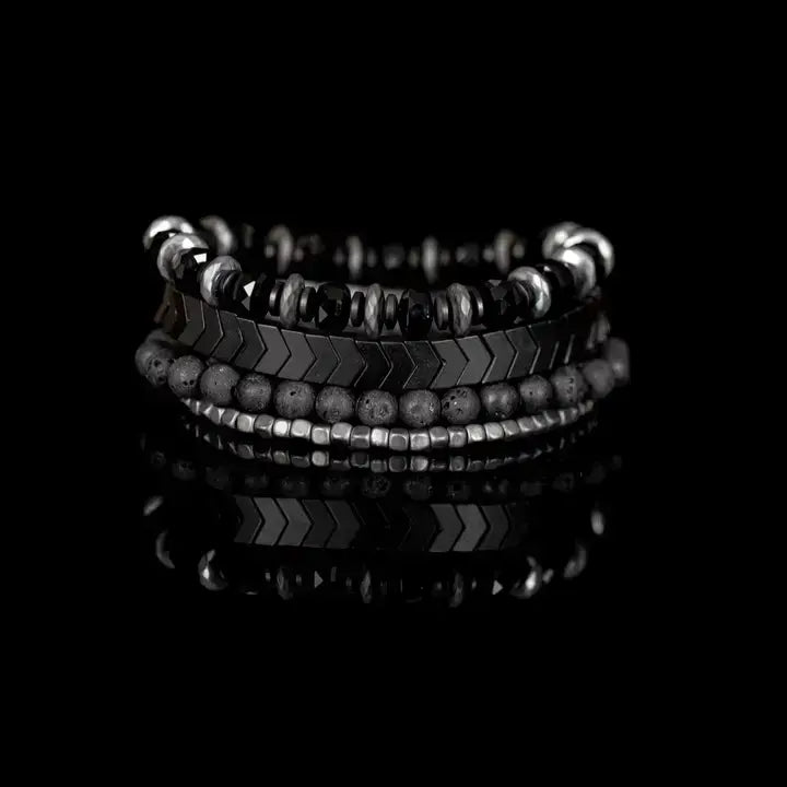 Men’s layered bracelet set featuring faceted black crystal beads, black and gray marbled stone beads, gunmetal chevron metal beads, matte black lava stone beads, and silver-tone hematite spacer beads, stacked in a bold monochromatic luxury design on a white background.