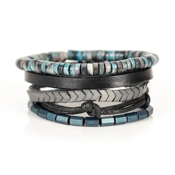 Blue and black multi-layer men’s bracelet set featuring silver chevron metal bar, blue-grey stone beads, black leather band, braided cord, and metallic hematite cube beads on a light background.
