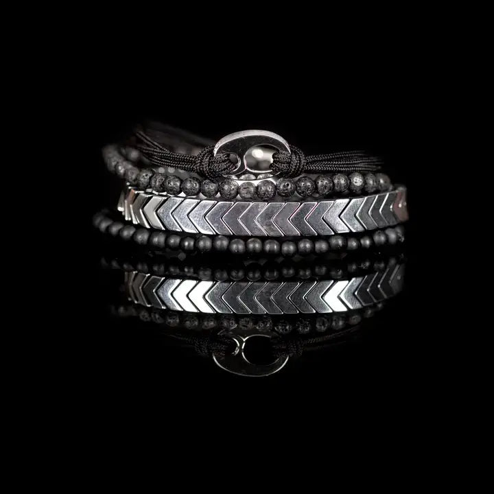 Black and silver layered men’s bracelet set with silver chevron metal strand, lava stone beads, matte black beads, and braided rope wraps on white background.