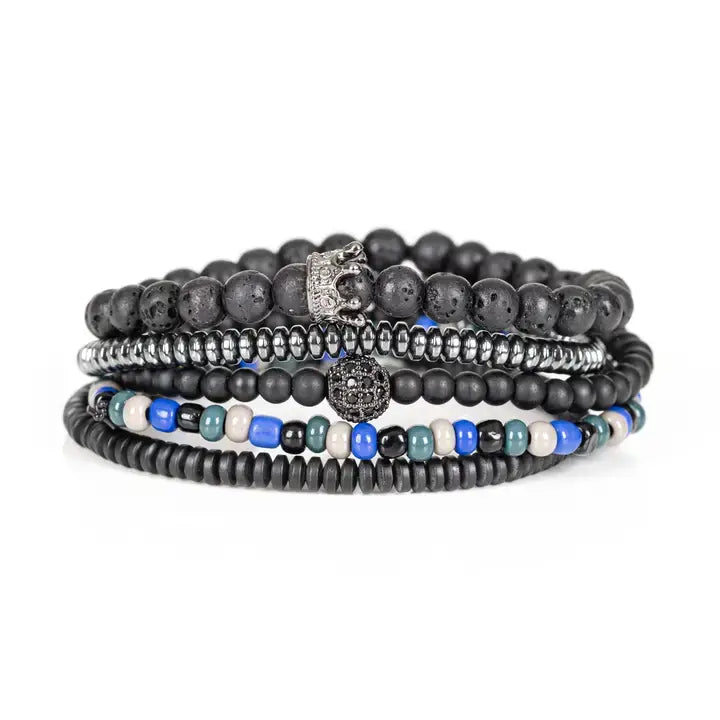 Black multi-layer men’s bracelet featuring lava stone beads, metallic hematite strands, crystal crown centerpiece, blue and white accent beads, and layered black bead details on a light background.