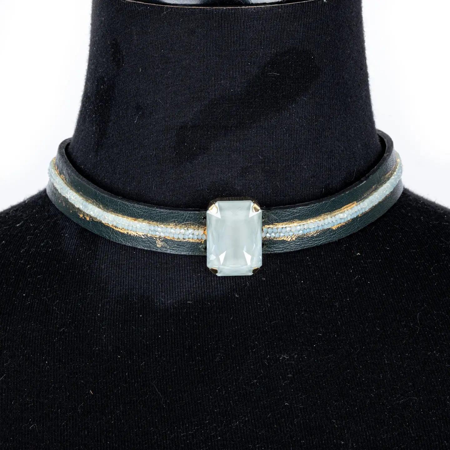 Black leather choker with a central rectangular white crystal and subtle gold and crystal detailing, displayed on a white background.