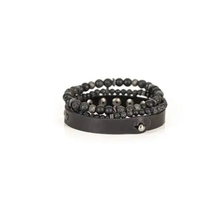 Black multi-layer men’s bracelet set featuring studded leather band, matte onyx beads, lava stone, faceted hematite accents, and layered black beaded strands on a light background.