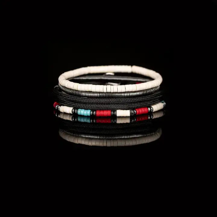 Men’s layered bracelet set featuring black braided cord, white heishi beads, turquoise and red disc beads, silver-tone accents, and hematite spacer beads, stacked in a contemporary bohemian luxury design on a white background.