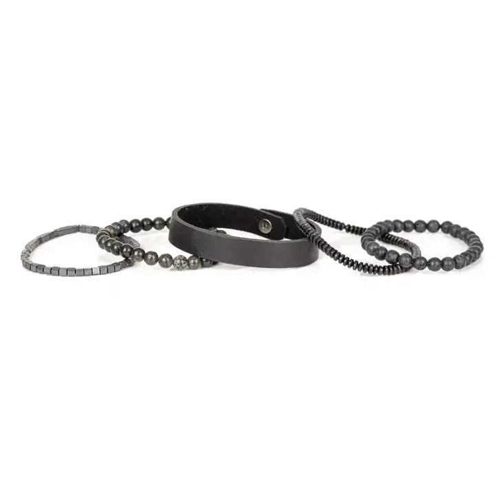 Men’s layered bracelet set featuring a black leather cuff, matte black lava stone beads, dark gray natural stone beads, black heishi spacers, faceted black crystal beads, and hematite cube beads, stacked in a sophisticated monochromatic luxury design on a white background.