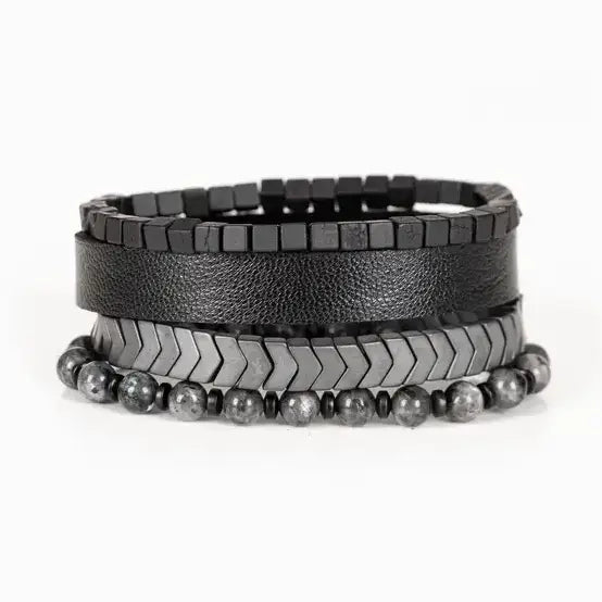 Men’s layered bracelet set featuring a black textured leather cuff, gunmetal cube bead bracelet, gunmetal chevron metal beads, and gray marbled natural stone beads, stacked in a bold industrial luxury design on a white background.