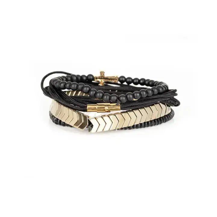 Black multi-layer men’s bracelet set featuring matte onyx beads, braided black rope, crystal cross centerpiece, gold chevron metal bar, and layered metallic accents on a light background.