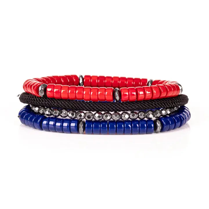 Men’s layered bracelet set featuring vibrant red and royal blue heishi beads, black braided cord, faceted hematite crystal beads, and gunmetal spacer accents, stacked in a bold contemporary luxury design on a white background.