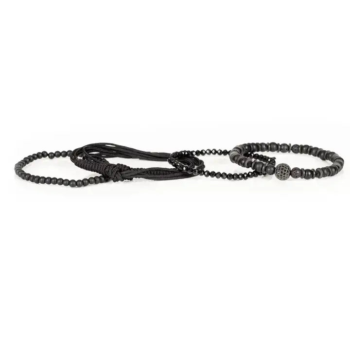Black layered men’s bracelet set with matte black beads, faceted crystal accents, braided rope wraps, and pavé centerpiece bead on white background.