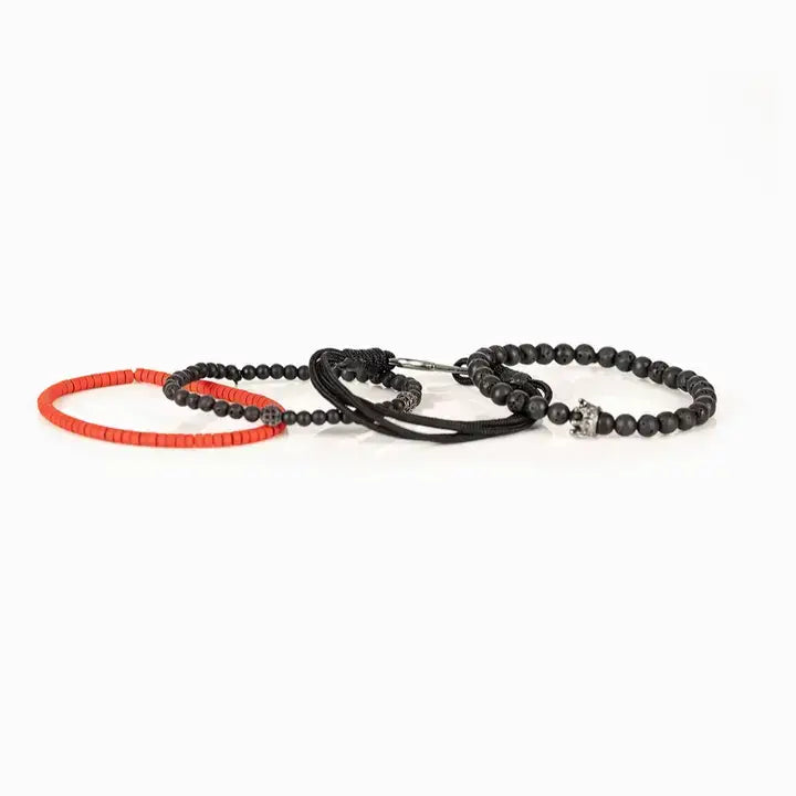 Men’s layered bracelet set featuring matte black lava stone beads, black braided cord, black onyx-style beads, gunmetal accent beads, a crown charm centerpiece, and vibrant red heishi beads, stacked in a bold contemporary luxury design on a white background.