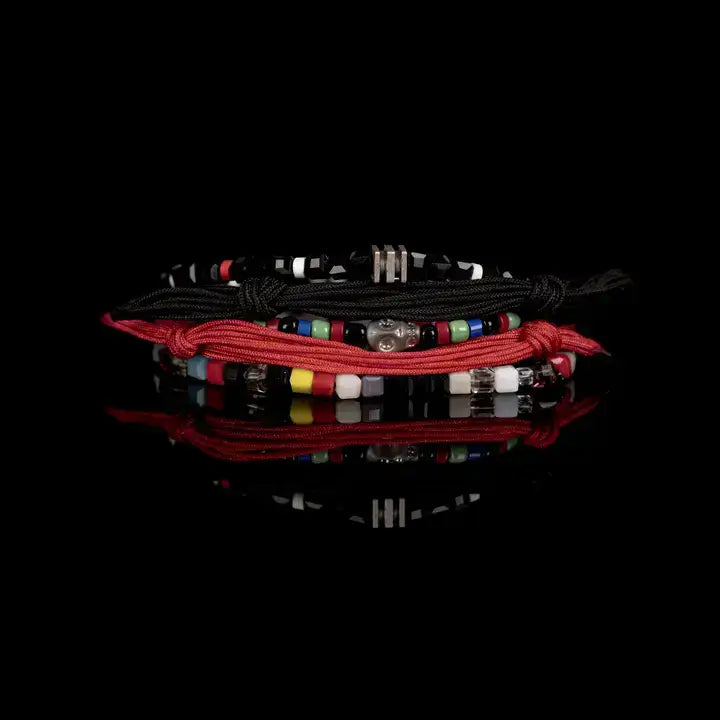 Black and red multi-layer men’s bracelet set featuring braided rope bands, faceted black geometric beads, metallic accents, and multicolor bead details on a light background.