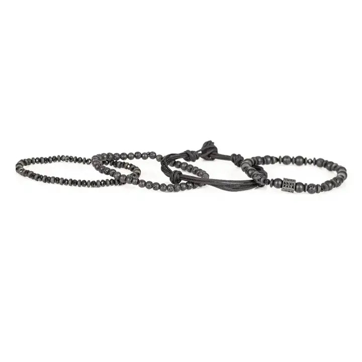Black layered men’s bracelet set with lava stone beads, matte black beads, crystal accents, braided rope wraps, and pavé square centerpiece on white background.