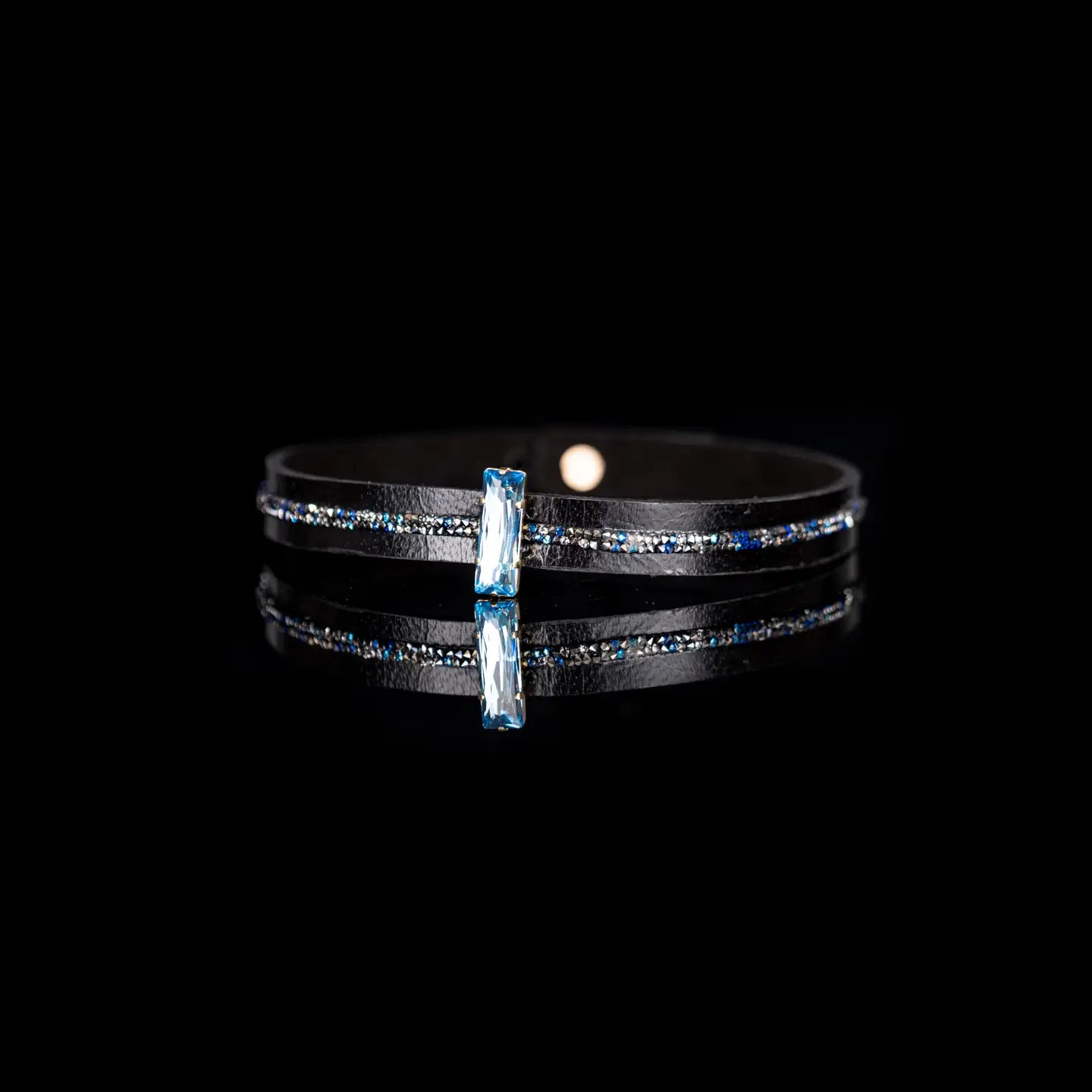 Black leather choker with a central blue crystal and fine rhinestone detailing along the band, displayed on a white background.