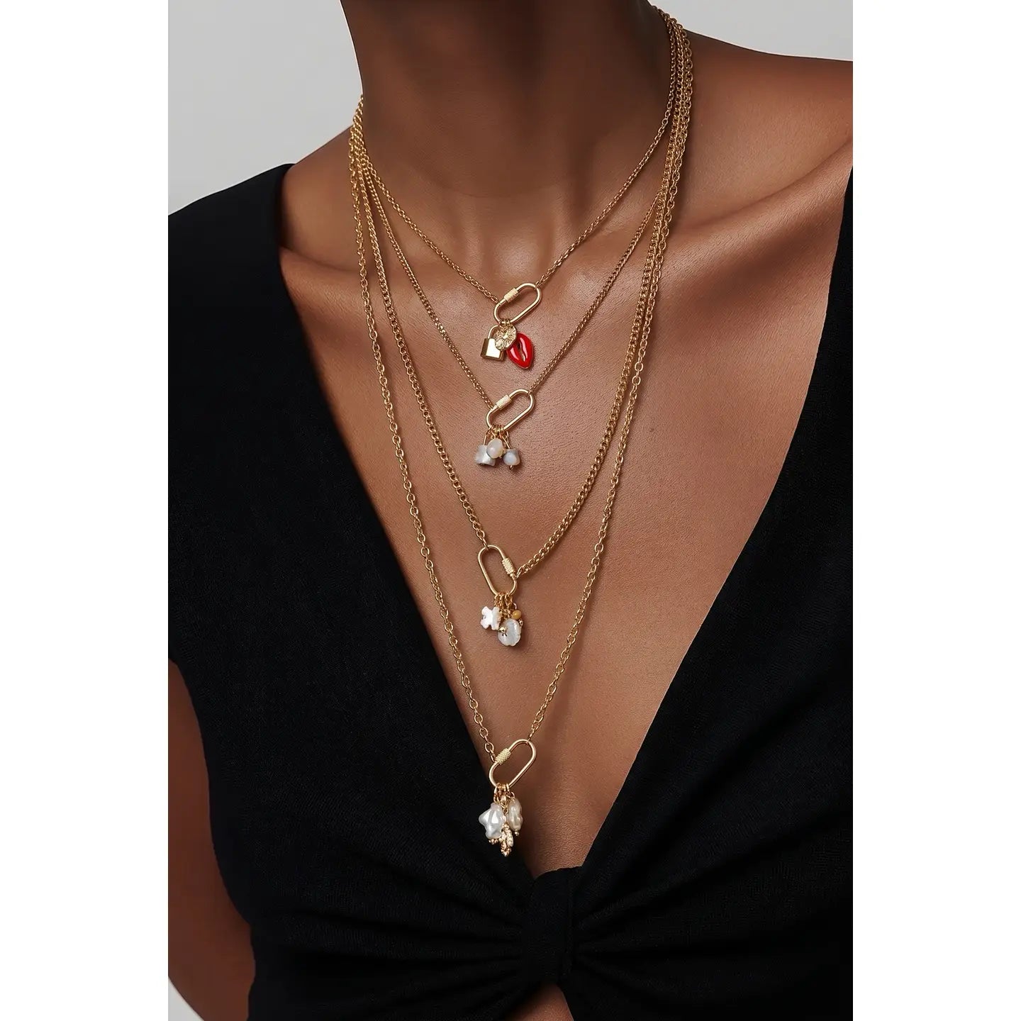 Layered gold necklace with three chains and small charm details on white background.