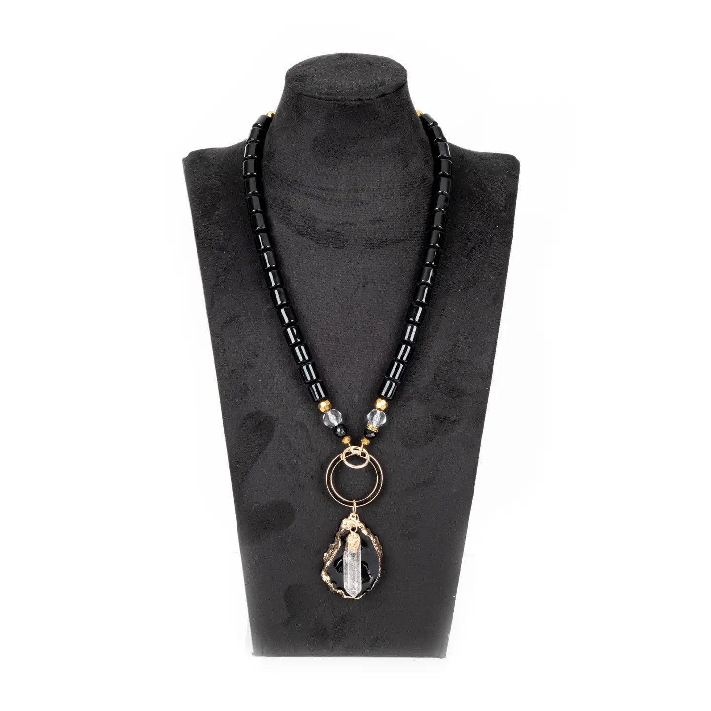 Black beaded necklace with gold ring connector and raw stone crystal pendant on white background.
