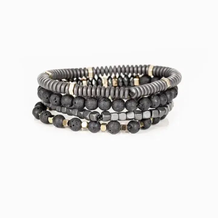 Men’s layered bracelet set featuring matte black lava stone beads, gray heishi beads, silver-tone hematite cube beads, faceted hematite crystal beads, and gold-tone spacer accents, stacked in a sophisticated industrial luxury design on a white background.