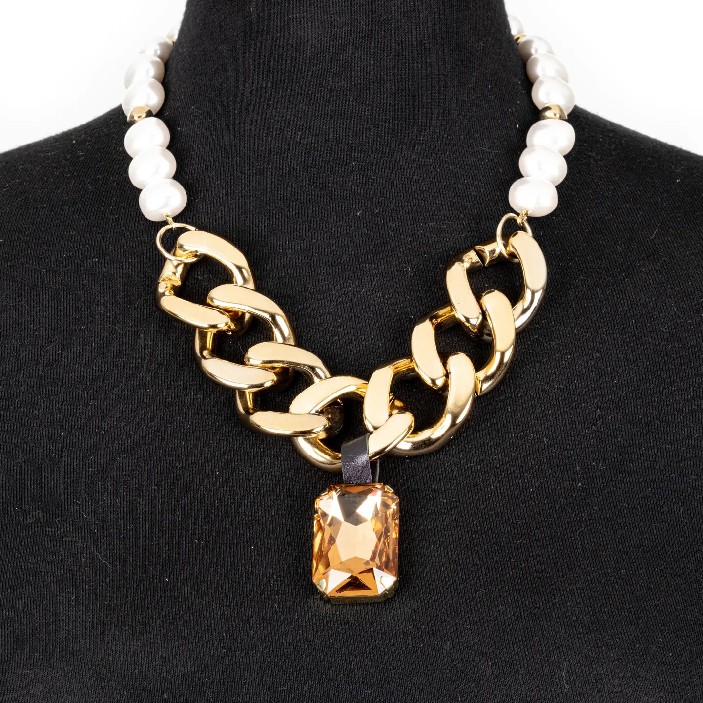 Gold chunky chain necklace with pearl detail and amber crystal pendant on white background.
